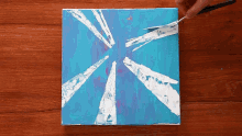 a person is painting a blue and white painting on a canvas