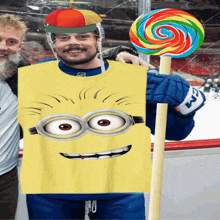 a man wearing a minion costume holding a lollipop