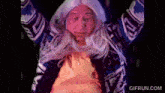 a man in a wig is dancing with his arms in the air .