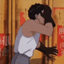 a man in a white tank top and black gloves is covering his face with his hands