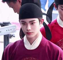 a man in a purple shirt and a black hat