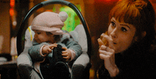 a woman is holding a baby in a car seat with a watermark that says haynes on it