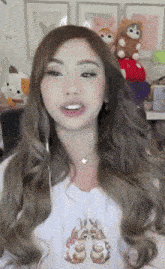 a woman with long brown hair is wearing a white shirt with a bunny on it .