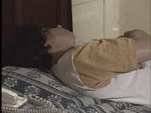 a man is laying on a bed next to a telephone