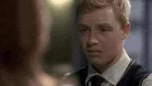 a young man in a vest and tie looks at a woman