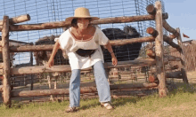 a woman wearing a straw hat stands in front of a fence