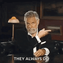 a man with a beard is sitting at a table and making a funny face .