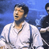 a man in a white shirt and suspenders is playing a banjo