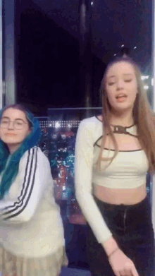 two young women are dancing in front of a window