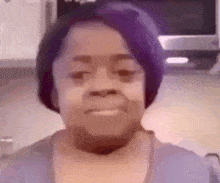 a close up of a woman 's face with purple hair .
