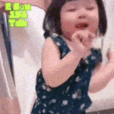 a little girl in a blue dress is being held by a person with ebon 194 tun written on the bottom