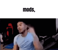 a man in a blue shirt is standing in front of a black background with the words `` mods '' written above him .