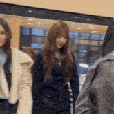 a group of women are standing in a room and one of them is wearing a black jacket .