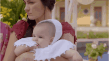 a woman is holding a baby in her arms who is wearing a white hat