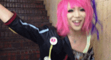 a woman with pink hair is wearing a black jacket and smiling .