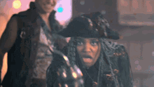 a woman with dreadlocks wearing a pirate hat looks surprised