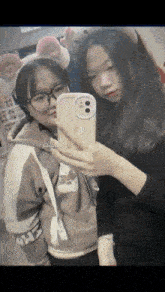 two girls are taking a selfie together with their cell phones .