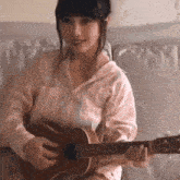 a woman is playing a guitar while sitting on a couch .