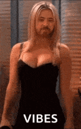 a woman in a black dress with a man 's face on her chest is standing in front of a window .