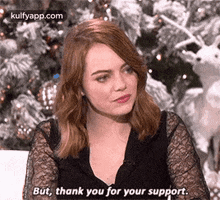 a woman is sitting in front of a christmas tree and talking to someone .