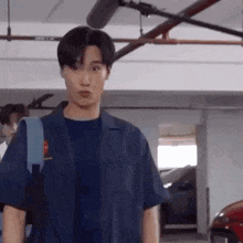 a young man is standing in a parking garage with a backpack on his back .