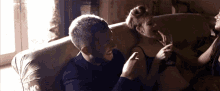 a man and woman are sitting on a couch and the man is laughing