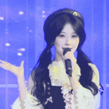 a woman singing into a microphone with a blue background