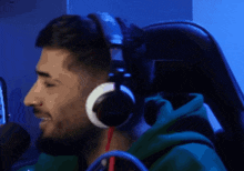 a man wearing headphones and a green hoodie smiles