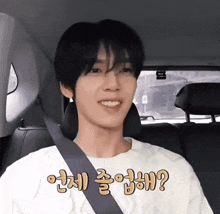 a man wearing a white shirt and a seat belt is smiling