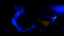a man is taking a cookie out of the oven in a dark room
