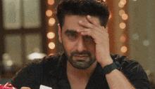 a man with a beard is covering his face with his hand and crying .