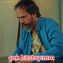 a man with a beard is wearing a blue shirt and says çok hastayimm