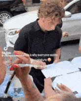a man with curly hair is signing a piece of paper
