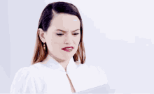 a woman in a white shirt is making a funny face while reading a piece of paper
