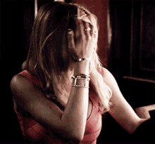 a woman covering her face with her hand wearing a ring and bracelets