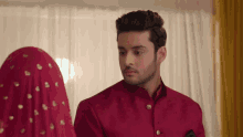 a man in a red suit looks at a woman in a red dress