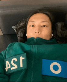 a man laying on a couch wearing a green jacket that says ast on it