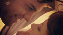 a close up of a man and woman kissing on a bed with a 4hd logo in the corner .