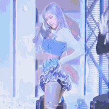 a woman in a strapless top is dancing on a stage in front of a purple background .
