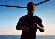 a man in a black tank top is running in front of a body of water
