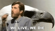 a man in a suit and tie is singing into a microphone while holding a bird 's head .