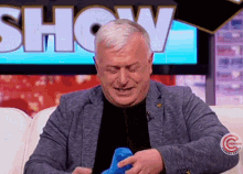 a man sitting on a couch in front of a screen that says show