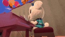 a stuffed animal is playing a pink piano with balloons in the background