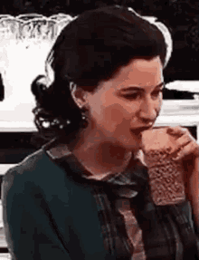 a woman in a green jacket is drinking a glass of wine .