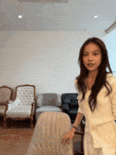 a woman in a white sweater stands next to a white chair