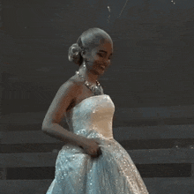 a woman in a white dress is smiling and holding her skirt