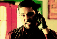 a man talking on a cell phone with a glove on his hand