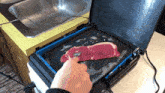 a person is cooking a steak on a griddle in a kitchen