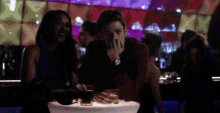 a man and a woman are sitting at a table in a bar with drinks .