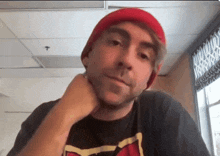 a man wearing a red beanie and a black t-shirt with a fox on it